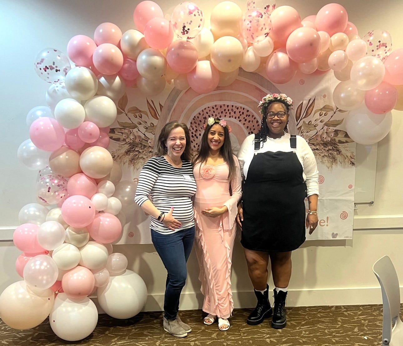 Courtney Three expecting mothers posing in front of balloons at a baby shower event