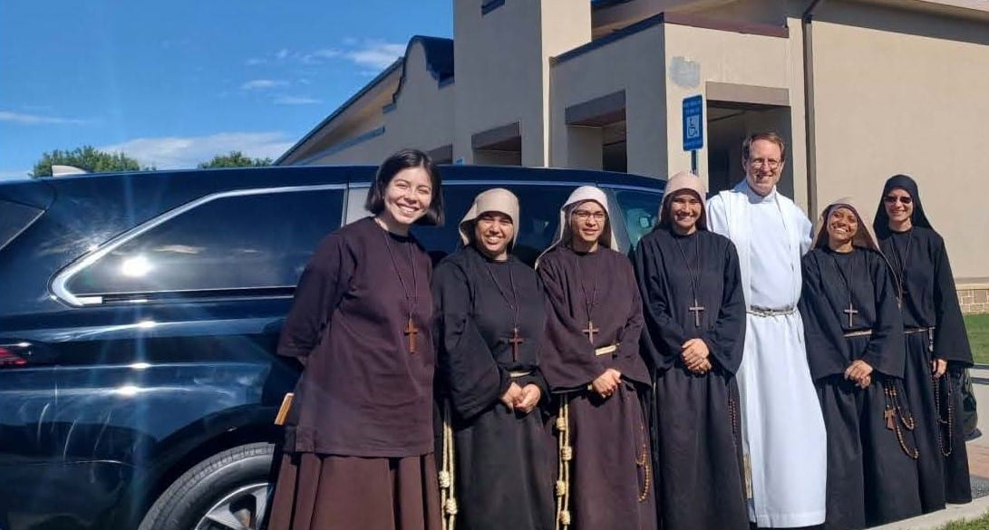 Sisters Poor Of Jesus Christ With Newly Donated Van Six women in religious garments and one Catholic priest in religious garments smiling for the camera in front of a vehicle