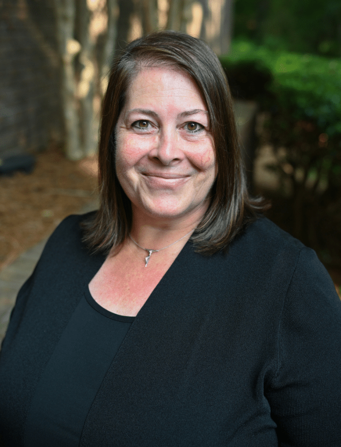 Bridgett Calia headshot of a woman posing in front of elevated landscaping