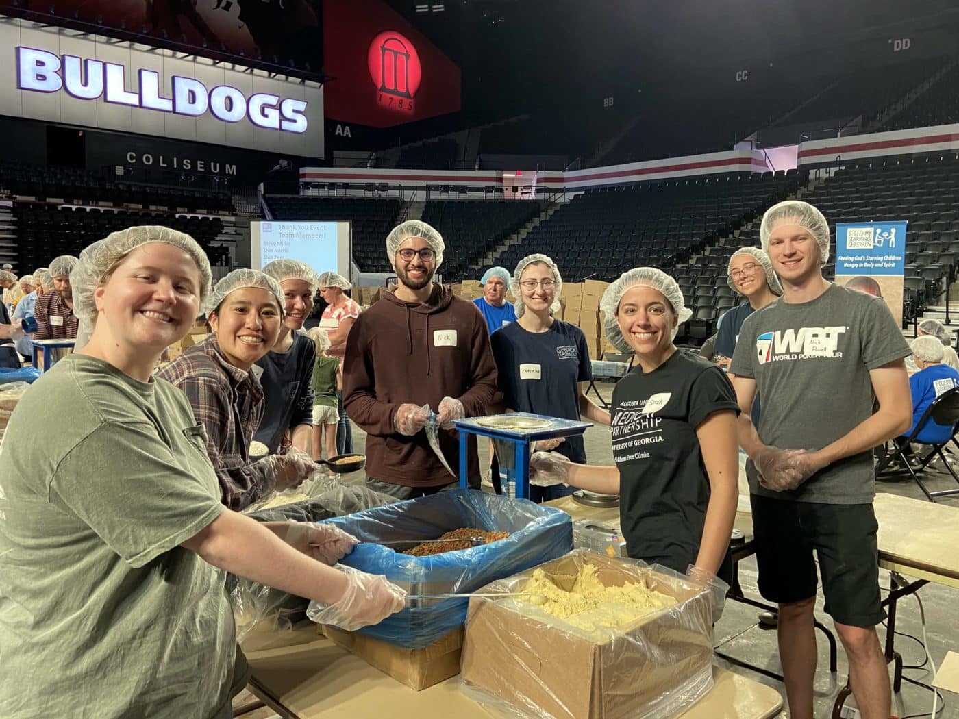 A group of workers packing meals stop to smile and pose for the camera