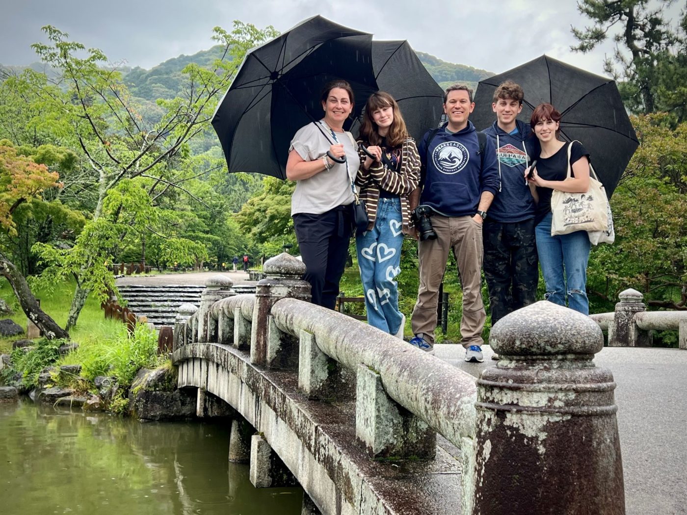 A family of five poses on a bridge in a nature area