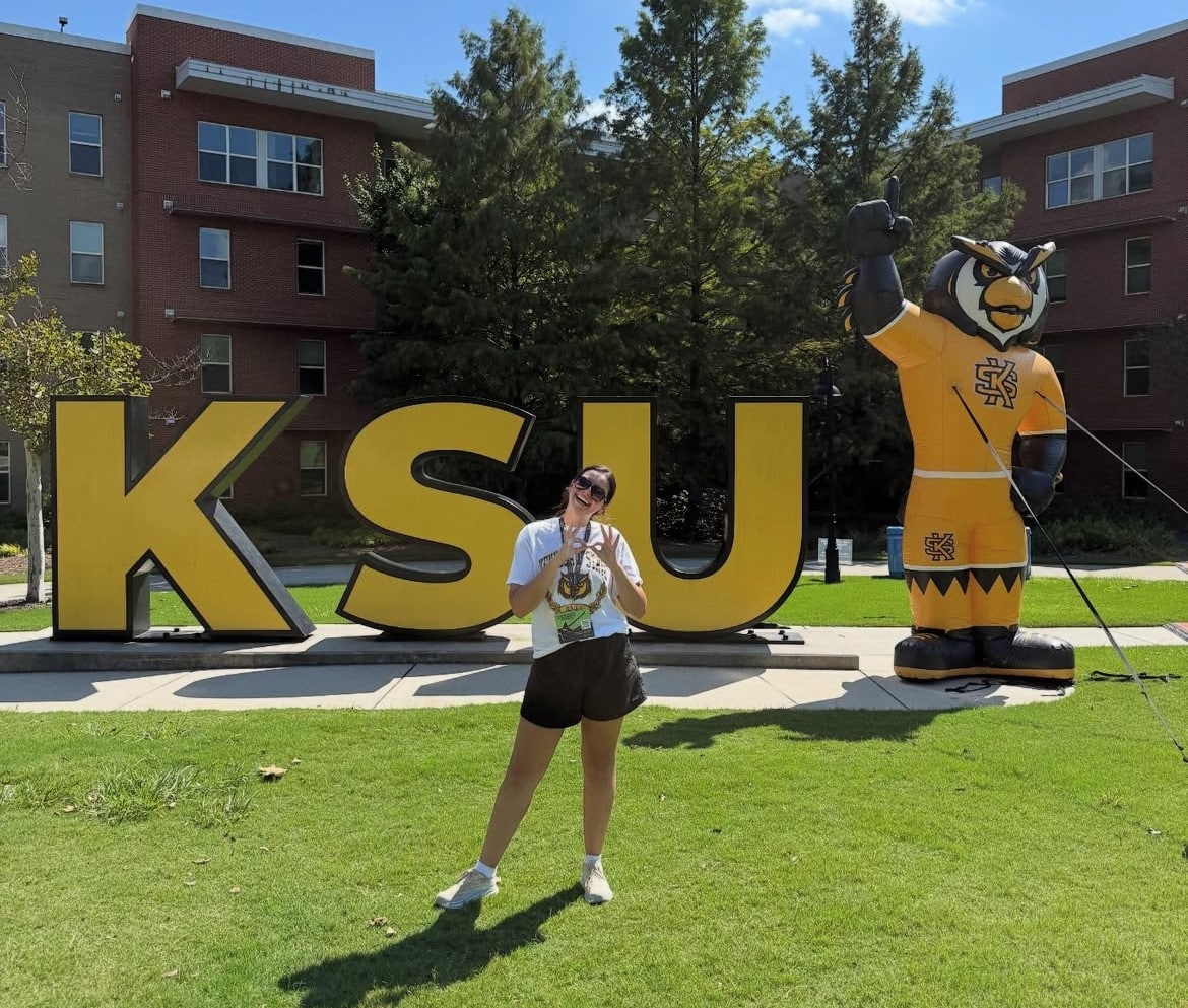 Woman poses in front of a KSU sign