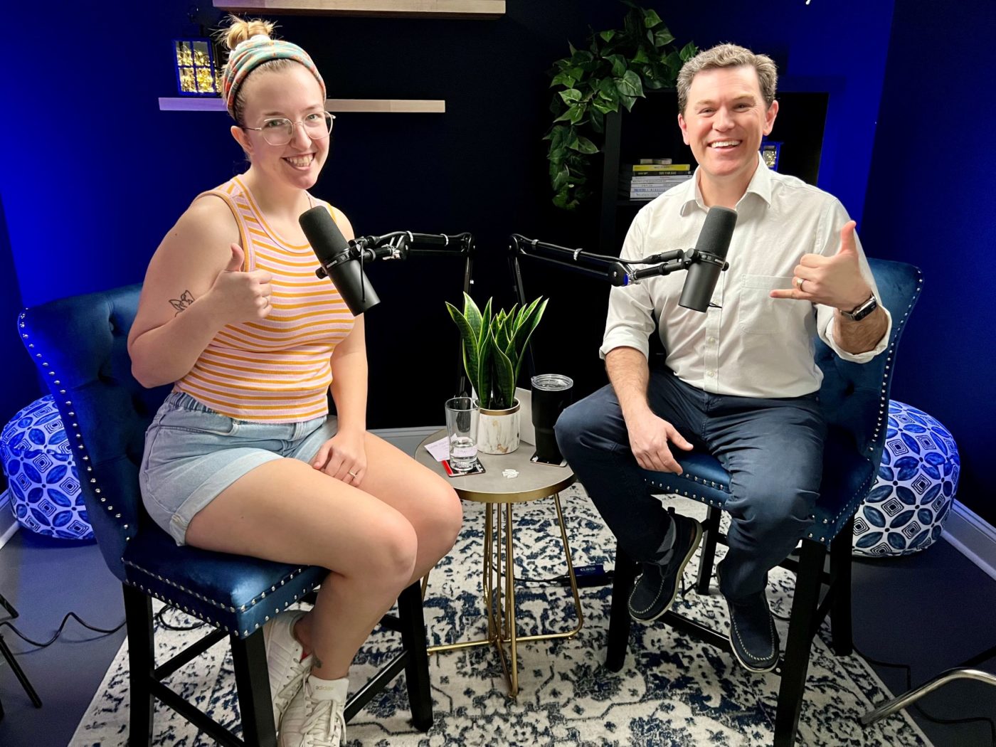 Two people smile and pose in a podcast studio