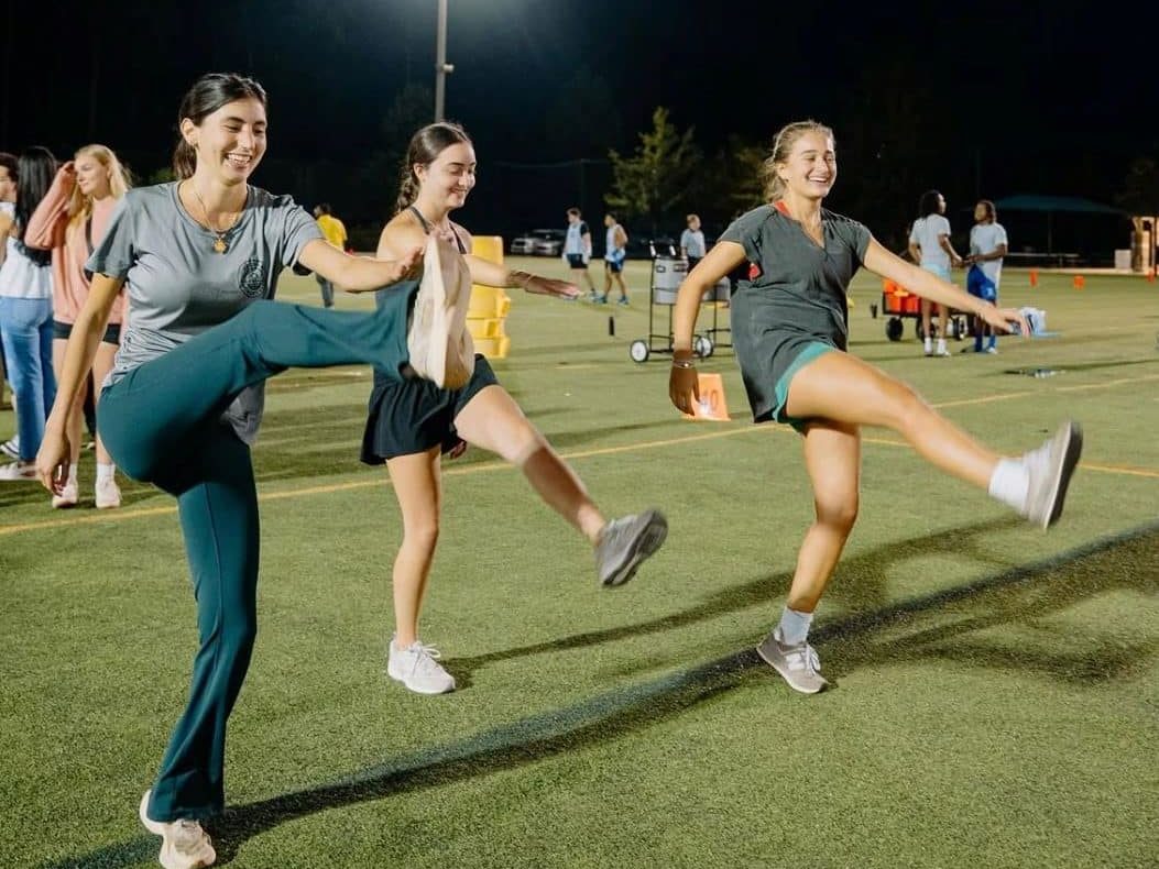 3 students stretching on a field