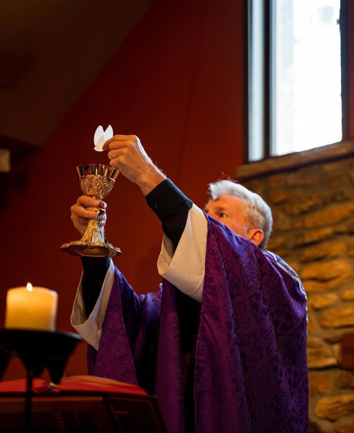 A priests holds up the Eucharist and Eucharistic Chalice