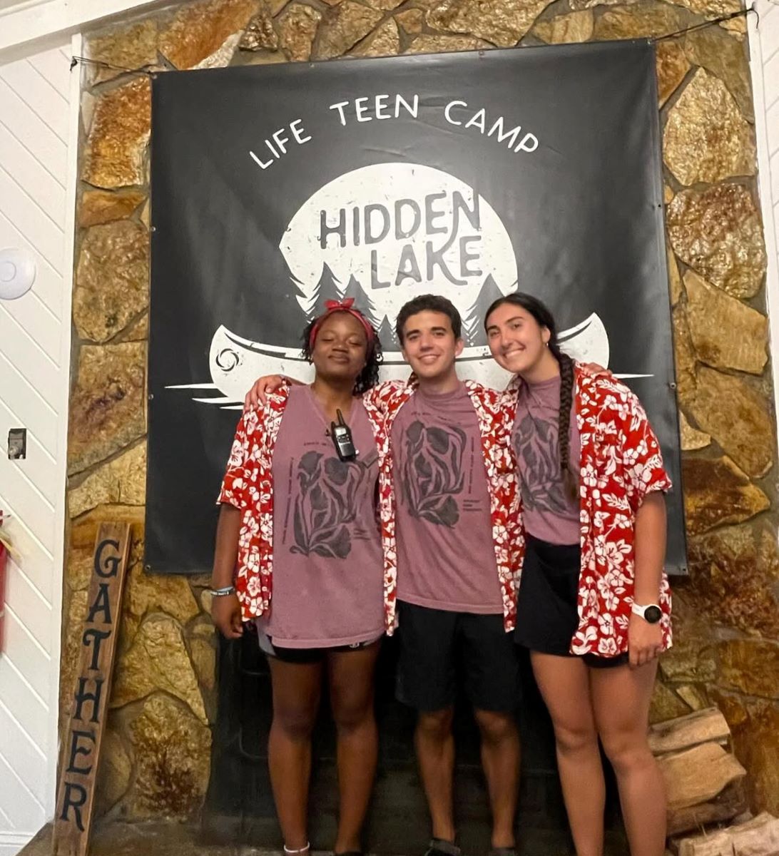 3 students post in front of a retreat sign