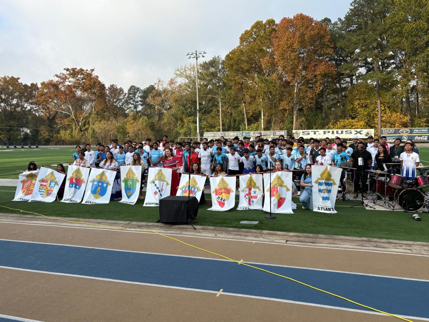 People pose together on a soccer field behind different archdiocesan crests