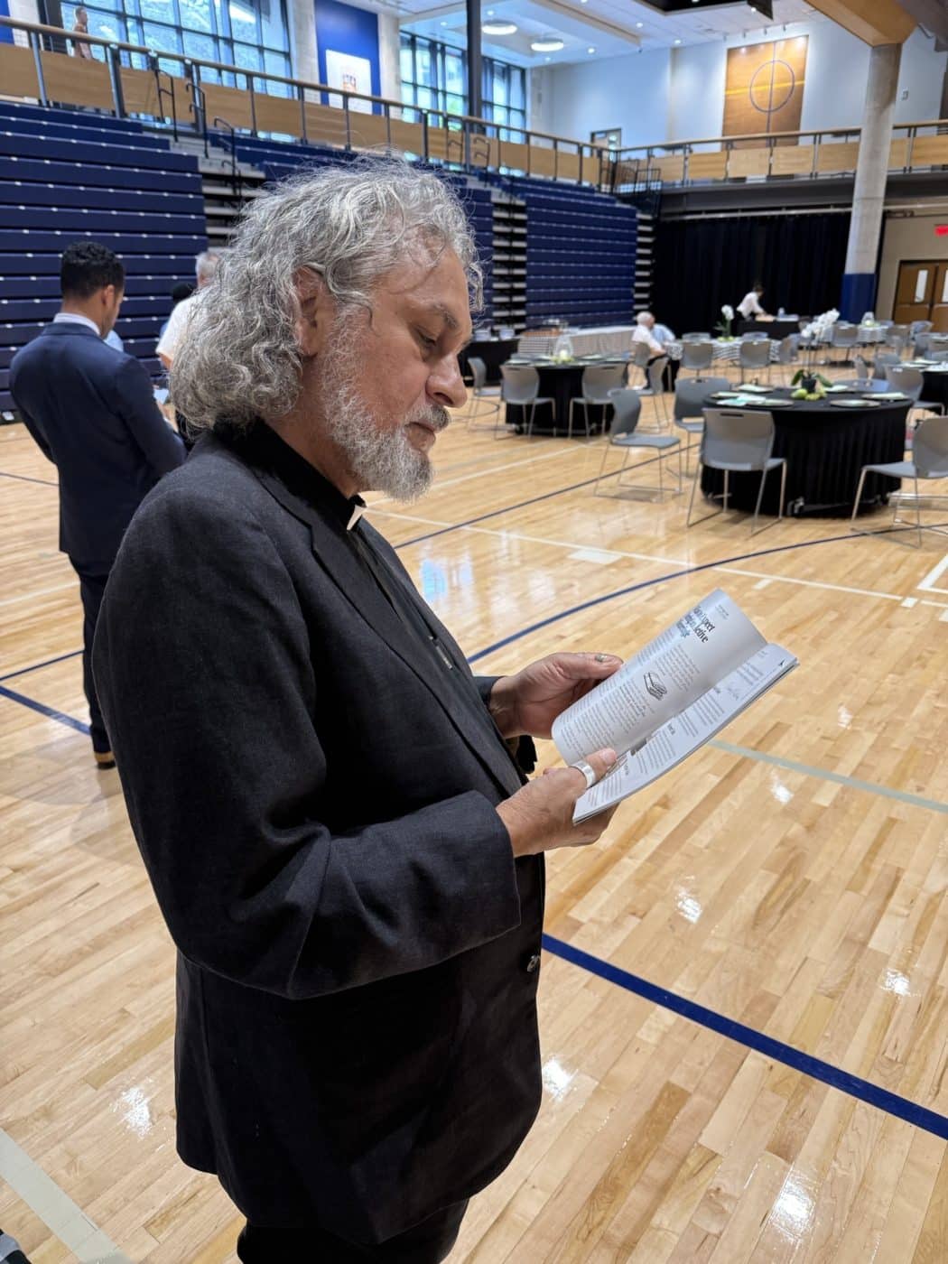 a priest reads a book in a gym