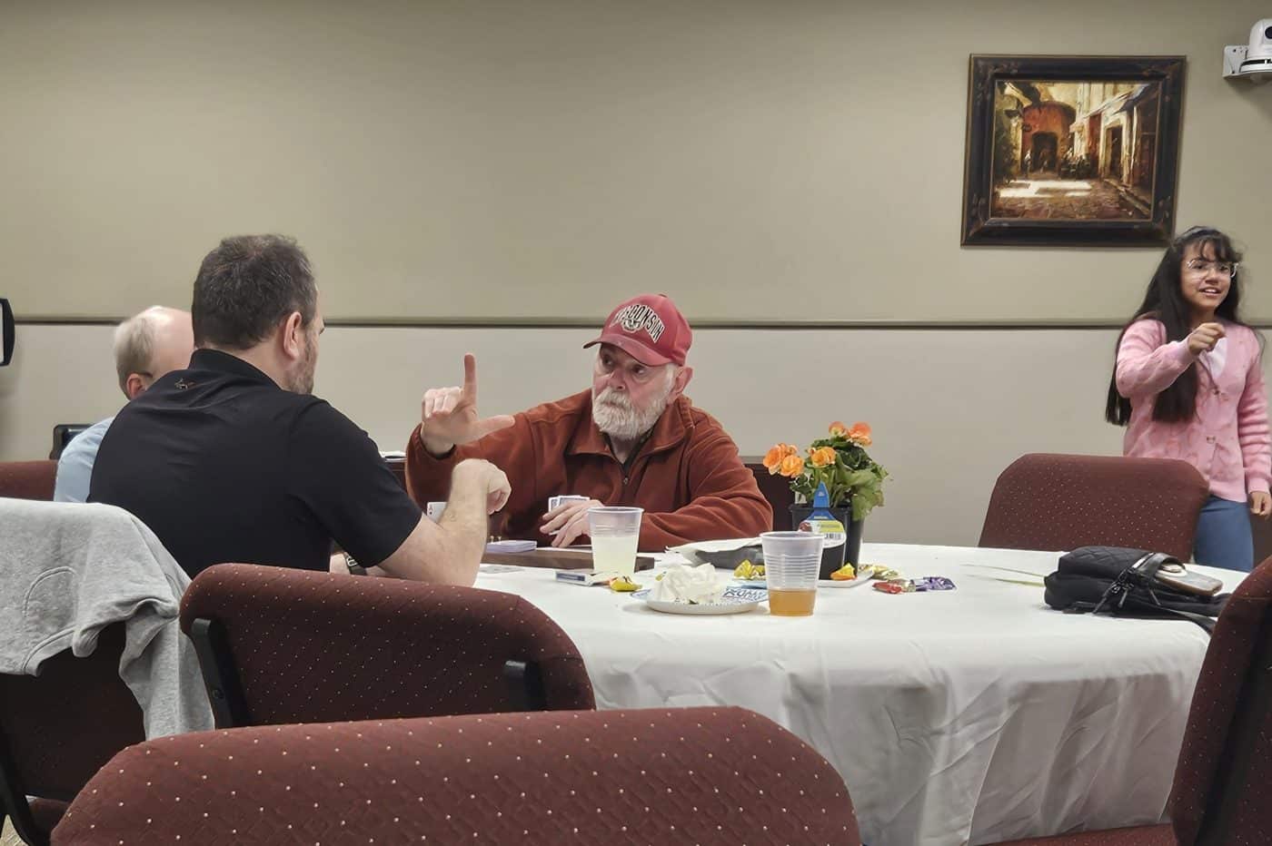 men at a table communicate through American Sign Language