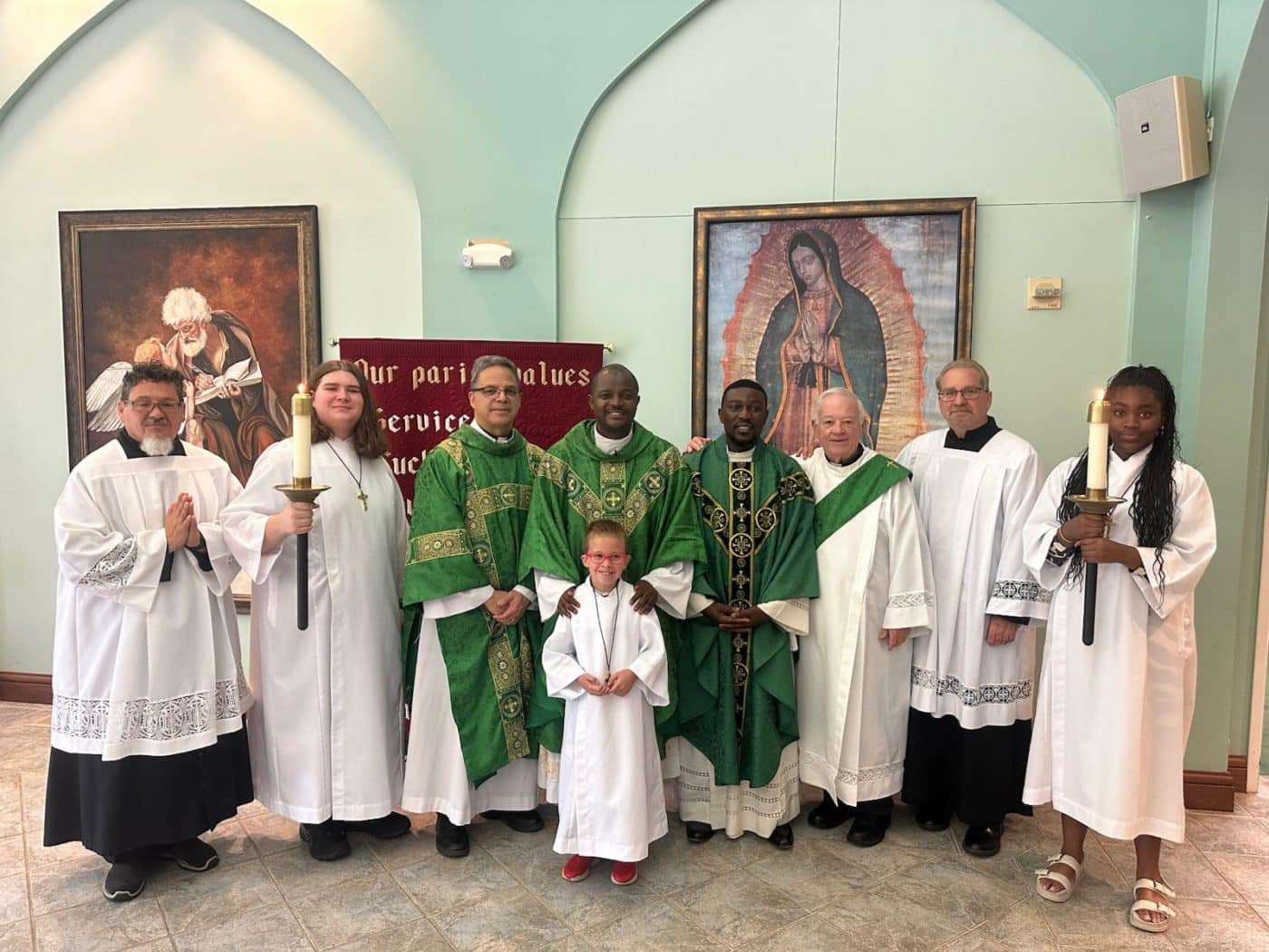 church leaders and servers pose together in front of Catholic artwork