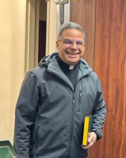 man in casual clergy attire smiles at the camera