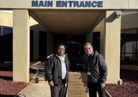 two men stand outside of a building that says Robert A. Deyton Detention Facility Main Entrance